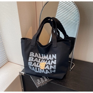 Close-up of black canvas tote with yellow bear print and letter patterns on a shelf