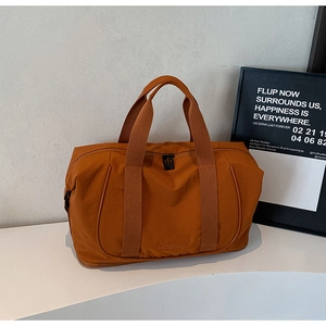 Détail du sac de voyage caramel avec coutures et logo Wellalbag sur le présentoir
