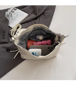 Spacious interior of minimalist cream shoulder bag with stripe lining and zip pocket