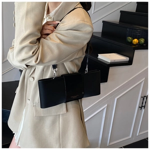 Detail of minimalist black rectangle shoulder bag with gold lettering on premium leather