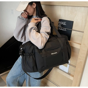 Détail du sac de voyage en nylon noir avec étiquette et bandoulière réglable