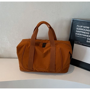 Gros plan détaillé du sac de voyage en nylon caramel avec logo et fermeture éclair en métal