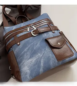 Close-up of vintage denim backpack with brown leather accents and silver hardware