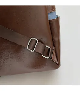 Close-up of brown textured leather backpack with silver buckle and woven strap