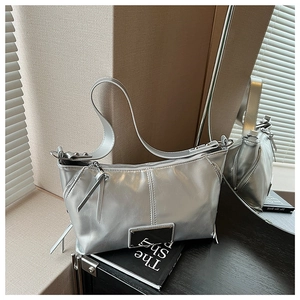 Detail of silver metallic tote bag showing glossy texture and decorative zipper features