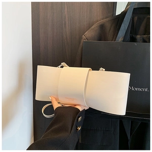 Detail view of cream-white leather bow-shaped shoulder bag with matte finish and fine strap