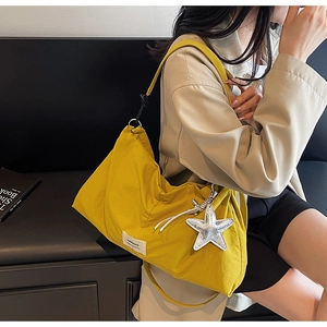 Detailed view of yellow canvas tote bag with starfish charm and brand logo tag