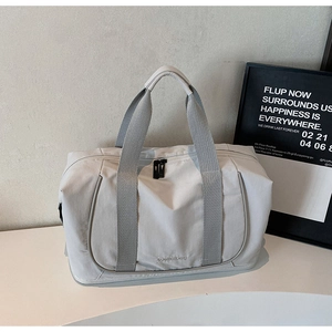 Détail du sac de voyage gris clair avec poignées renforcées et texture en tissu résistant