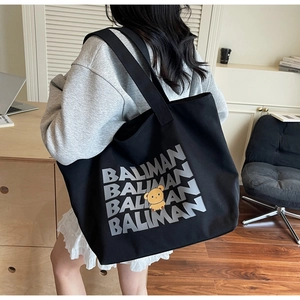 Side view of a large black canvas tote bag with cartoon bear and Baliman text print