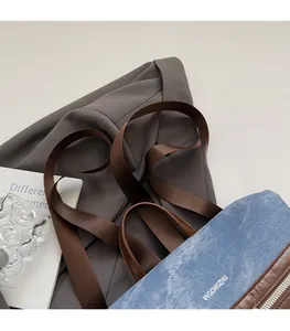 Detail of blue denim backpack with wide brown woven straps and leather handle texture
