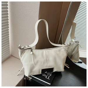Detail of cream white shoulder bag with soft leather texture and stylish tassel zipper