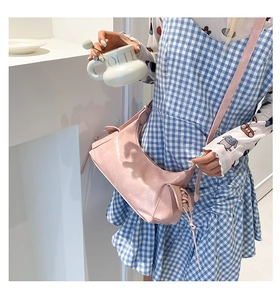 Détail du sac bandoulière en cuir verni rose avec laçage latéral et finition brillante
