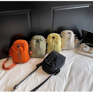 Flat lay of colorful nylon drawstring crossbody bags in orange green yellow and white