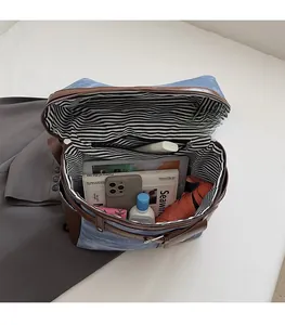 Large denim and leather tote bag showing spacious striped interior with tablet and phone