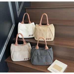 Detail showing embroidered logo and front pocket on canvas tote bags in four neutral colors
