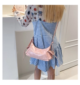 Borsa a spalla rosa lucida indossata, dettagli con coulisse e design a forma baguette