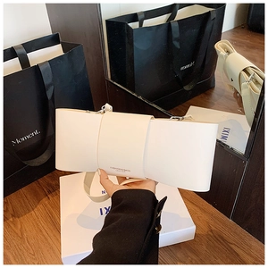 Detail showing creamy white bow-shaped PU leather shoulder bag held by hand