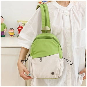 Close-up of mini canvas backpack in green and white worn as a crossbody chest bag