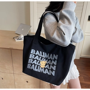 Detail view of large black canvas tote bag with BALIMAN print and cartoon bear pattern