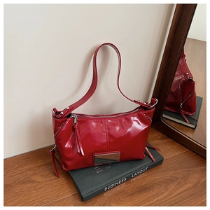Detail of red patent leather tote bag on black book in minimalist interior scene