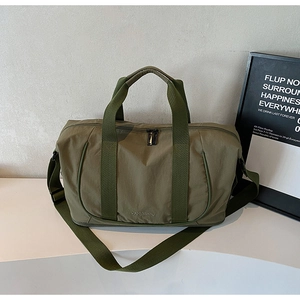 Sac de voyage vert olive avec bandoulière réglable et poignées dans un décor épuré