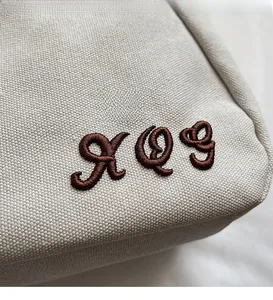 Detailed close-up of brown rope embroidery on cream minimalist canvas bucket bag