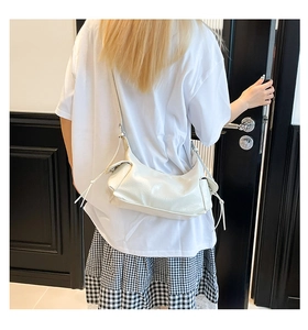 Borsa hobo bianca lucida con coulisse portata a spalla in un contesto minimalista