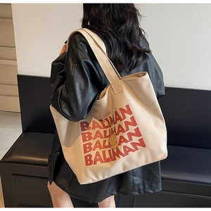 Detail of off-white canvas tote bag featuring red BALIMAN text and a yellow bear print