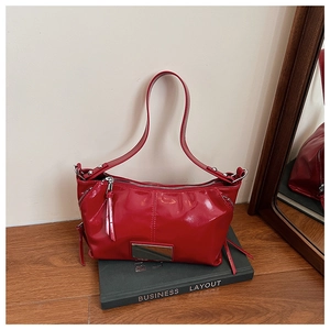 Detail of red glossy patent leather handbag with metal plaque and zip closure