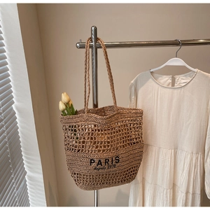 Detalle de bolso tote de paja tejida con estampado negro Paris depuis 1970 y malla calada