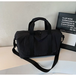 Détail du sac de voyage noir montrant les poignées renforcées et la poche zippée