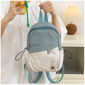 Détail d'un mini sac à dos bicolore bleu et beige avec cordon et emblème métallique
