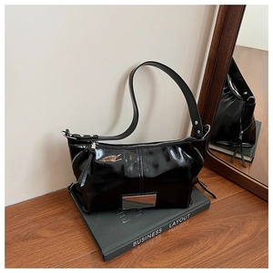 Detail of glossy black patent leather shoulder bag with silver buckle and metal plaque