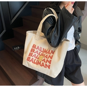 Close-up of beige canvas tote with red lettering and cute yellow bear illustration