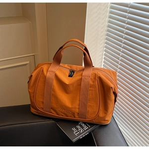 Détail du sac de voyage orange montrant la texture en nylon ripstop et le logo