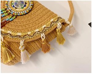 Close-up of bohemian woven straw bag with colorful mandala beadwork and tassels