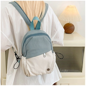 Close-up of a stylish light blue and cream small backpack with a retro metal logo detail