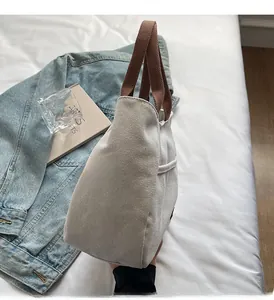 Detail of high-density canvas tote with reinforced brown straps and embroidered lettering