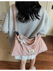 Pink large-capacity nylon tote bag with star pendant and logo label worn by a model