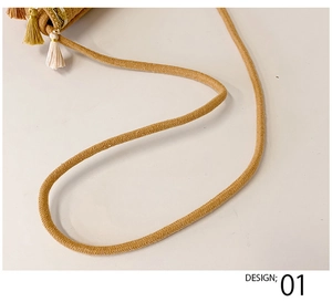 Detail of bohemian straw bag showing textured woven rope strap and multi-tone tassels