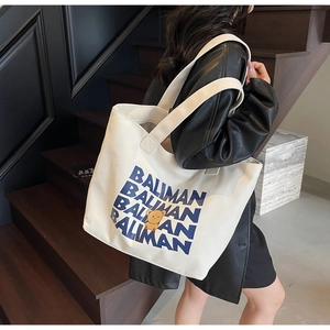 Detail of white large-capacity canvas tote bag featuring blue letter print and bear