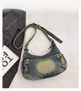 Detail of washed blue denim hobo bag featuring retro distressed edges and metal zipper