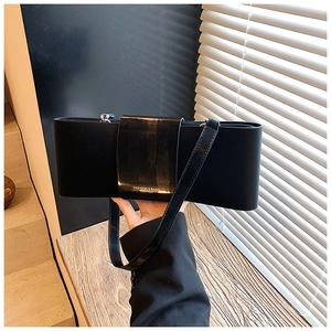 Detail of black bow-shaped shoulder bag with wide buckle and polished leather finish