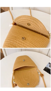 Detail of hand-woven straw bucket bag showing magnetic closure and tassel accent