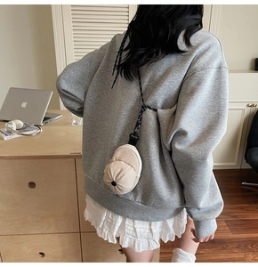 Mini creative baseball cap shaped crossbody bag worn over a grey hoodie sweatshirt