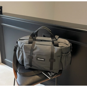 Gros plan du sac de voyage gris avec poche zippée et compartiment latéral à cordon durable
