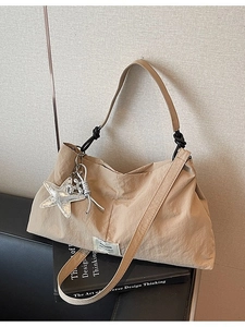 Large beige canvas tote bag with a silver star charm and knotted shoulder strap