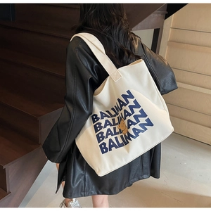 Detail view of large white canvas tote bag with BALIMAN lettering and bear motif