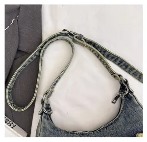 Detail of adjustable denim shoulder strap and vintage washed blue fabric with silver zipper