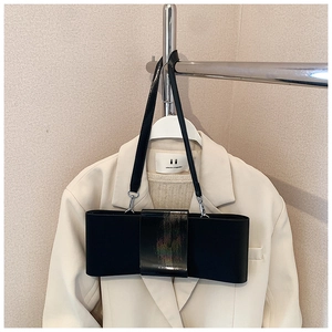 Detail of a black bow-shaped underarm bag with sleek leather strap and minimal aesthetic
